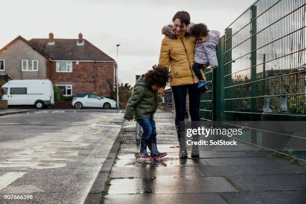 splashing in a puddle - uk street stock pictures, royalty-free photos & images