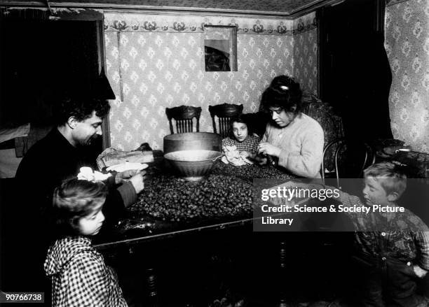 Immigrants shelling nuts, separating the edible nut kernel from the shell. One of a series of photographs featuring tenement children, taken by Lewis...