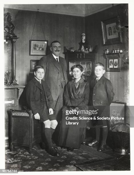 Snapshot photograph of a family in their living room, taken by an unknown photographer in about 1915. Originally a shooting term, the word 'snapshot'...