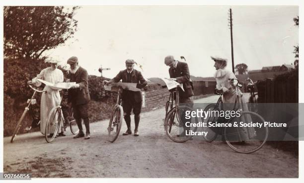 Snapshot photograph of a group of cyclists on a country road consulting their maps, taken by an unknown photographer in about 1906. A craze for...