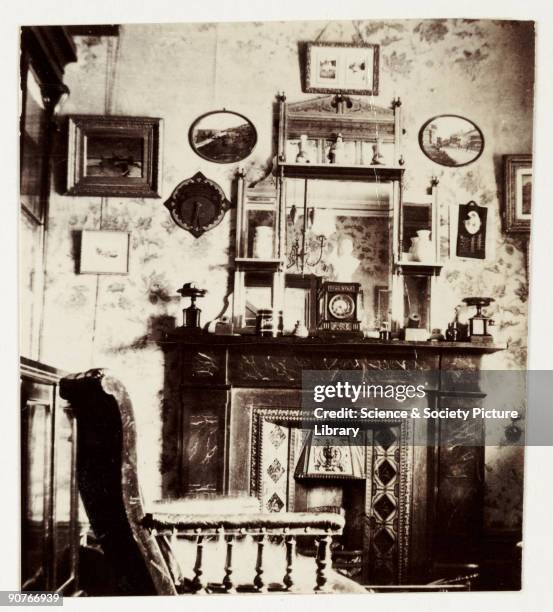 Snapshot photograph of a fireplace and overmantle in a living room, taken by an unknown photographer in about 1900. Originally a shooting term, the...