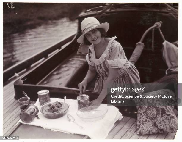 Snapshot photograph of a woman opening tins of �My Lady� apricots on a boat, taken by an unknown photographer in about 1925. Originally a shooting...