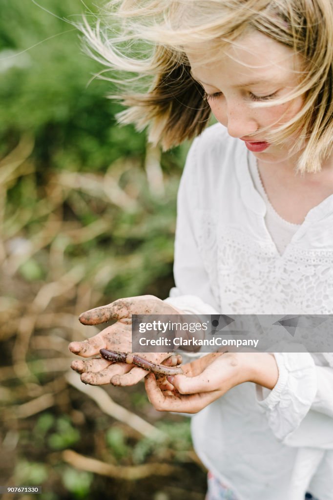 Young Girl Learning and Playing With An Earthworms in Her Kitchen Garden.