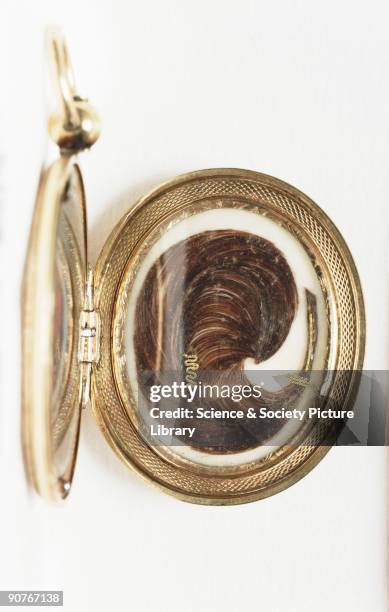Lock of hair bound with gold thread and encased in a gold locket, created by an unknown maker in about 1850. The exterior of the gold locket has an...