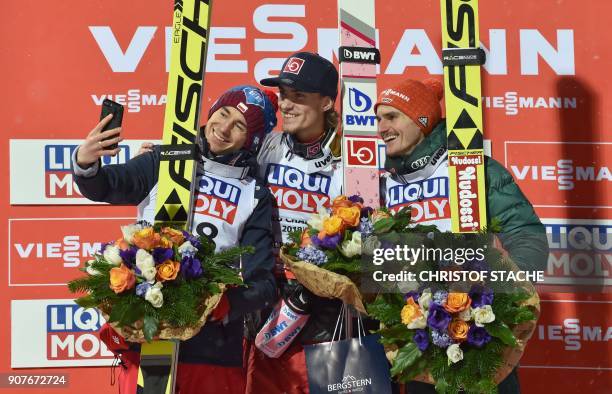 Poland's Kamil Stoch makes a selfie with the winner Norway's Daniel Andre Tande and Germany's Richard Freitag as they celebrate on the podium after...