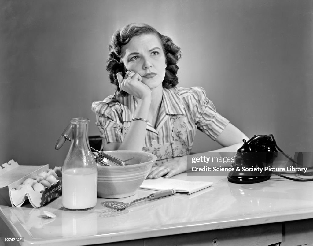 Woman writing a list at a work surface, 1956.