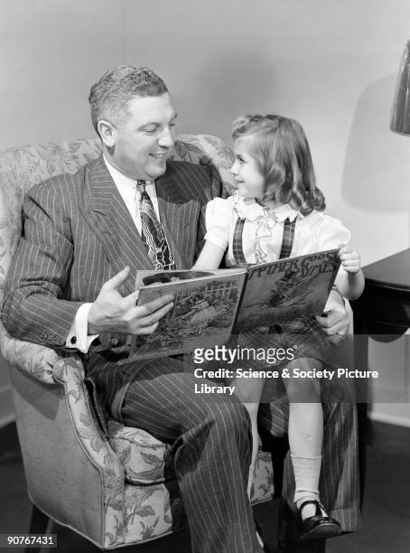 Photograph of a man reading a storybook to a little gril sitting on his knee, taken for Photographic Advertising Limited in 1949. This scene of happy...