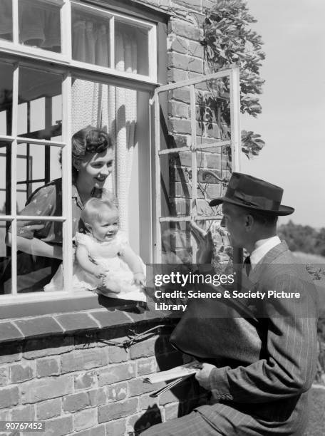 Photograph of a man waving goodbye to a woman and baby, taken by Photographic Advertising Limited in 1951. Photographic Advertising Limited was...