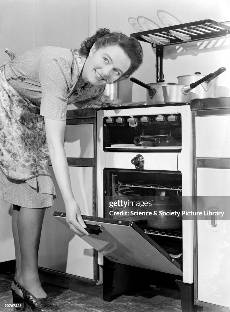 Woman checking food in the oven, 1950.