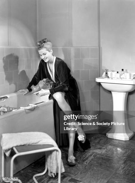 Photograph of a woman in a dressing gown running a bath, taken by Photographic Advertising Limited in 1950. This image was used by the South Eastern...