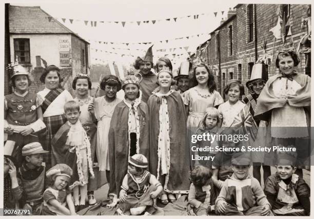 Photograph of children wearing fancy dress in Flint Street, Cardiff, taken by an unknown photographer in May 1937. This photograph is from an album...