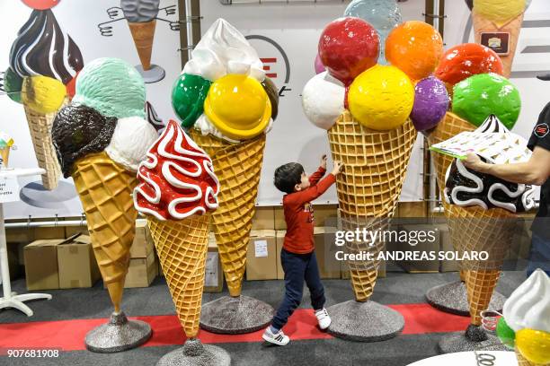 Child plays with giant ice cream statues during the 39th International trade Show of Artisan Gelato , Pastry, Bakery and Coffe World in Rimini, on...