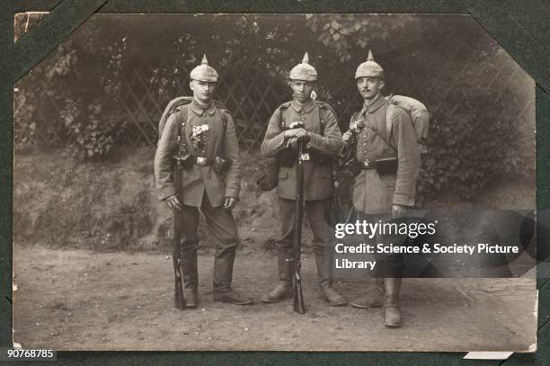 Photographic postcard of three German soldiers, taken by an unknown photographer in about 1914. These young soldiers' distinctive 'pickelhaube'...