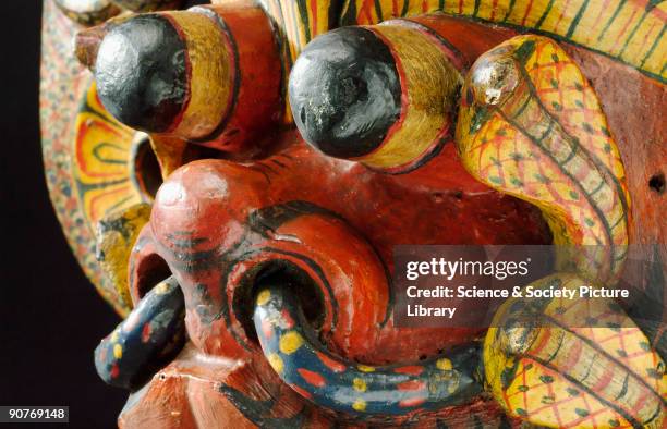 Large painted wooden polychrome mask representing a red-faced demon with cobra canopied headdress and cobras on lotus disc ear pieces, associated...