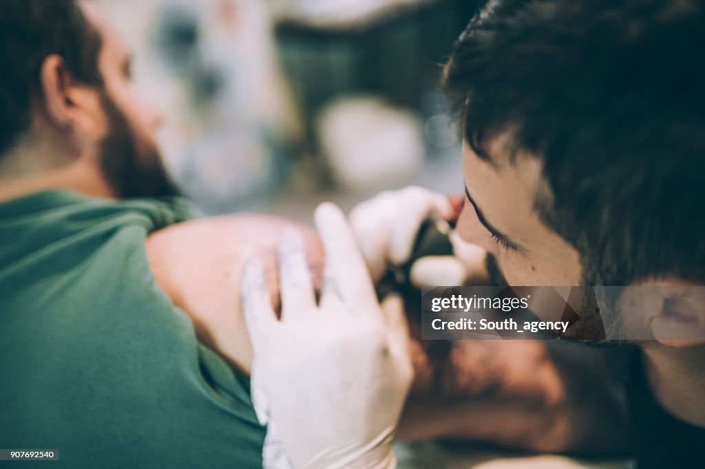 Artist tattooing a guy