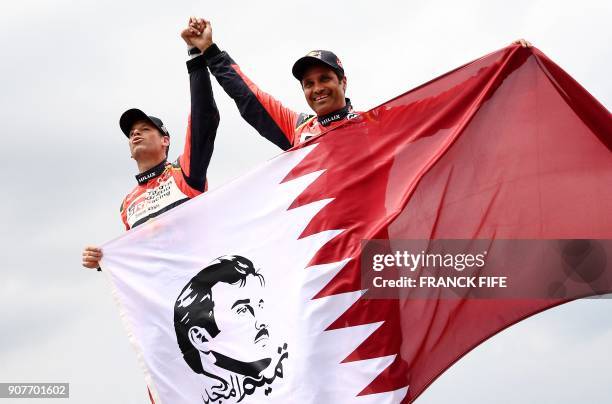 Toyota's Qatari driver Nasser Al-Attiyah and his French co-driver Mathieu Baumel celebrate as they hold Qatar's national flag depicting an image of...