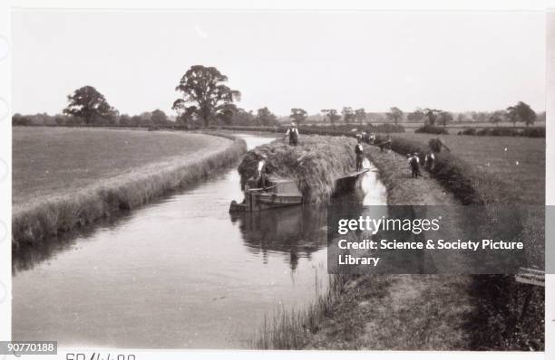 Outriggers fixed to a canal barge to carry a cargo of hay. A snapshot photograph of a narrowboat heavily laden with hay, taken by an unknown...