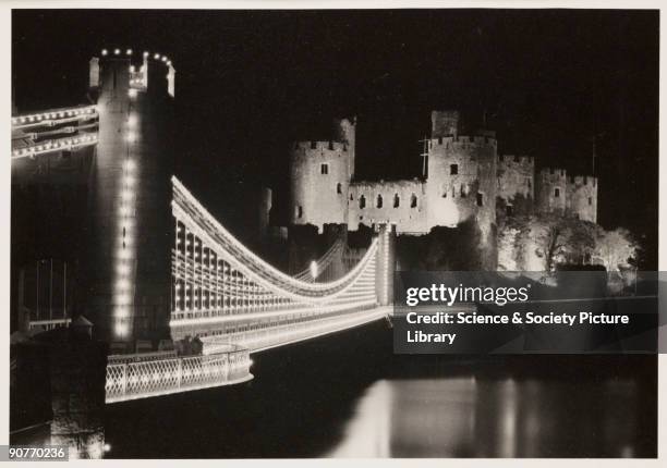 Photograph of the floodlit bridge and Castle in Conway, North Wales, taken by an unknown photographer in May 1937. This photograph is from an album...