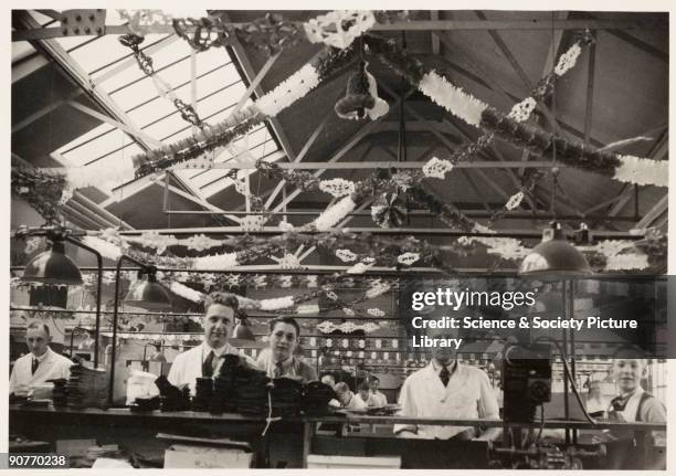 Photograph of workers at a shoe factory in Northampton, taken by an unknown photographer in May 1937. The factory has been decorated to celebrate the...