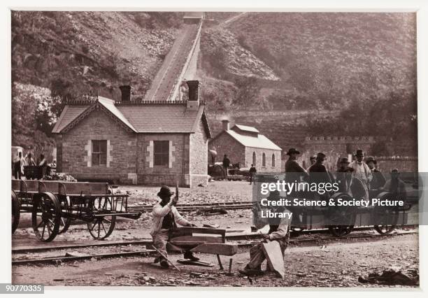 Quarrymen chiselling blocks of stone at the slate quarry in Llanberis, Wales. In the backgound is a funicular railway, possibly for transporting...