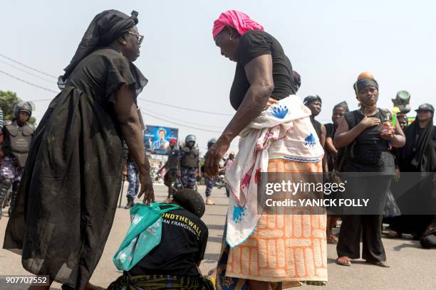 Togolese woman looks on as another sits on the street during a protest rally in the capital Lome against Togo's president on January 20, 2018. A...