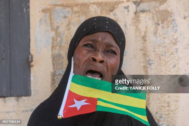 Togolese woman holds the national flag as she watches a protest rally by women in the capital Lome against Togo's president on January 20, 2018. - A...