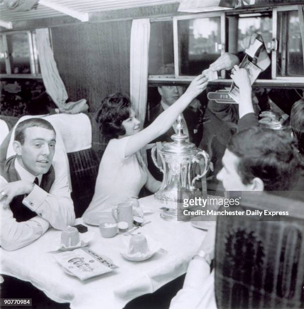 Ian St John with others sitting at a railway carriage table with a trophy on 2 May 1965. Ian St John was a Scottish footballer who started his...