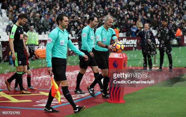 Referee Martin Atkinson picks up the match ball as he walks out with the match officials during the Premier League match between West Ham United and...