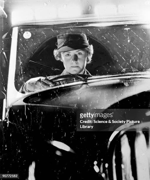 Photograph of a woman driving a car in the rain, taken by Photographic Advertising Limited in about 1950. This atmospheric - yet staged - photograph...