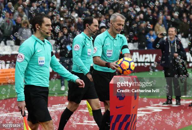 Referee Martin Atkinson picks up the match ball as he walks out with the match officials during the Premier League match between West Ham United and...