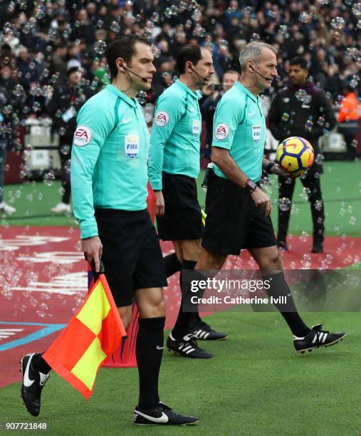 Referee Martin Atkinson picks up the match ball as he walks out with the match officials during the Premier League match between West Ham United and...