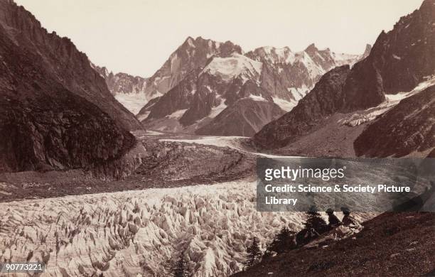 Albumen print showing two women and a man resting during a walk alongside the Mer de Glace , near Chamonix, with the summit of the Grandes Jorasses...