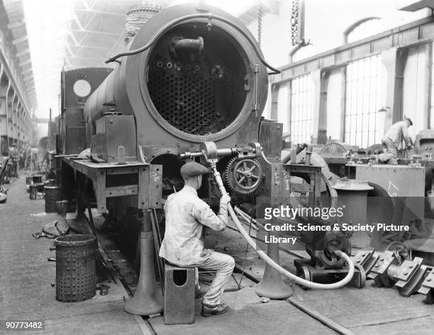 Worker using equipment in the erecting shop at Horwich works. This shop was also used for repairing locomotives and tenders and was well equipped...