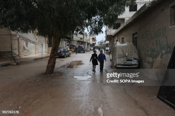 Boy and his sister seen walking under the rain in an old street in Mesraba. Despite the ongoing conflict in Syria, life in government-held parts of...