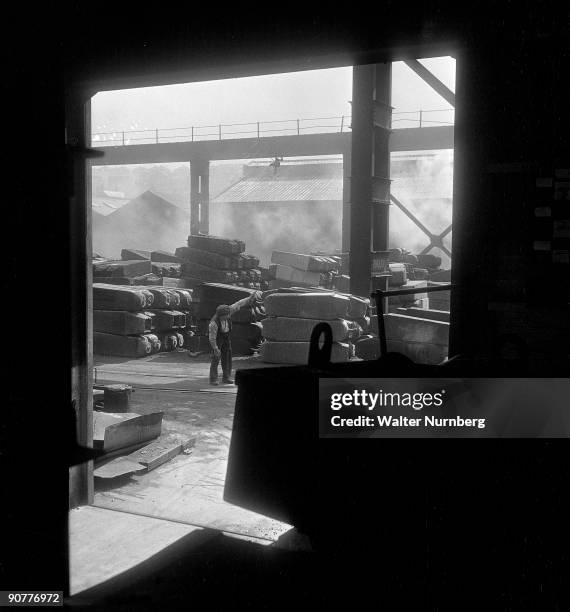 Looking from the electric furnace on to the plant yard where finished steel ingots are being cooled and stored ready for transport. United Steel was...
