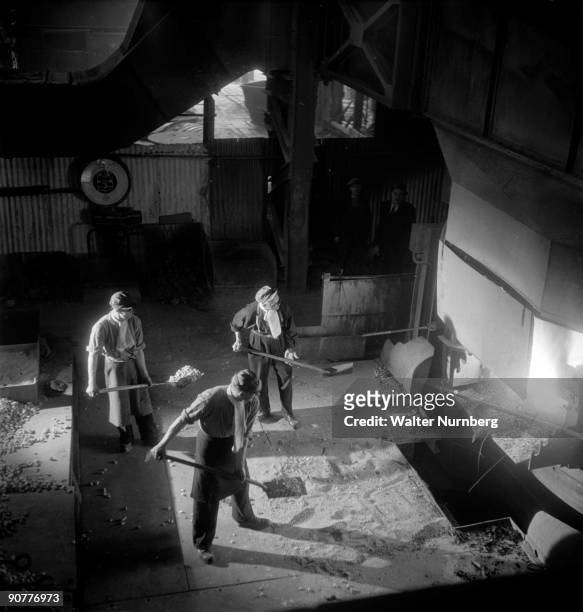 Three workers with shovels before a carbon arc furnace at the United Steel company United Steel was one of Britain's largest steel plants and a major...
