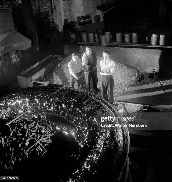 Three steel workers rake slag producted after a batch of molten steel is made at the charging end of a carbon arc furnace. United Steel was one of...