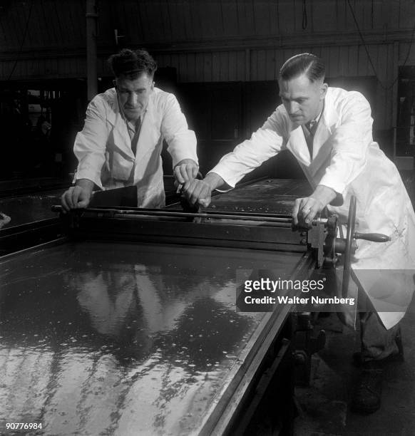 Two workers at the Mackintosh confectionary factory in Halifax skim the top of a toffee slab to ensure uniform thickness before it is set and cut in...