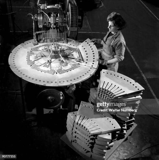 Female operator uses a jig to punch a series of hole in to segments to be used in turbine production. Photographed by Walter Nurnberg who transformed...