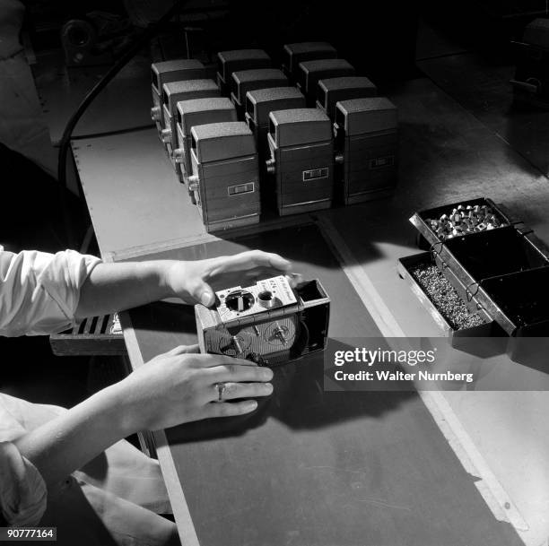 An assembly worker makes final tests to a batch of 8mm Bell and Howell clockwork cine cameras at the factory of British Acoustic Films. The Surrey...