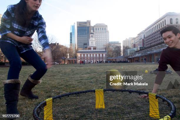 Friends play a lawn game in front of tourists waiting in line to see the Liberty Bell in front of the shuttered Independence Hall after the...