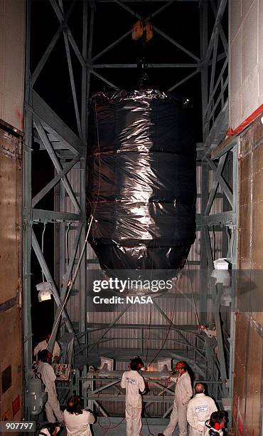 Inside the launch tower at Pad 17-A, Cape Canaveral Air Station, workers guide the Stardust spacecraft toward an opening to a Boeing Delta II rocket...