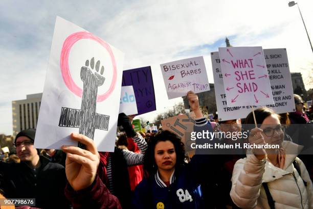 People hold up signs during the Denver Women's March on January 20, 2018 in Denver, Colorado.