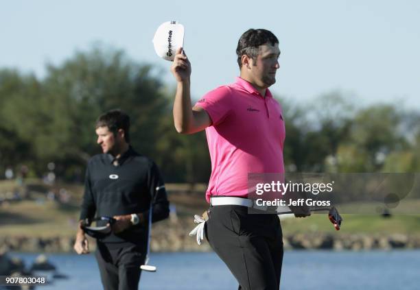 Jon Rahm of Spain finishes his round on the 18th green as Bubba Watson looks on during the third round of the CareerBuilder Challenge at the TPC...