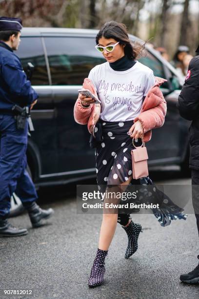 Melanie Darmon wears sunglasses, a pink puffer coat, a white t-shirt, a black lace mesh skirt with polka dots, outside Dior, during Paris Fashion...