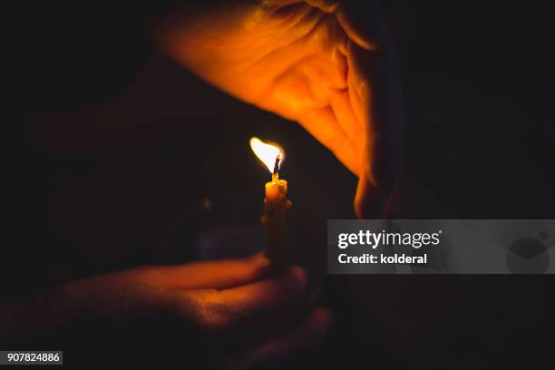 close-up on candle flame and woman hands - candela attrezzatura per illuminazione foto e immagini stock
