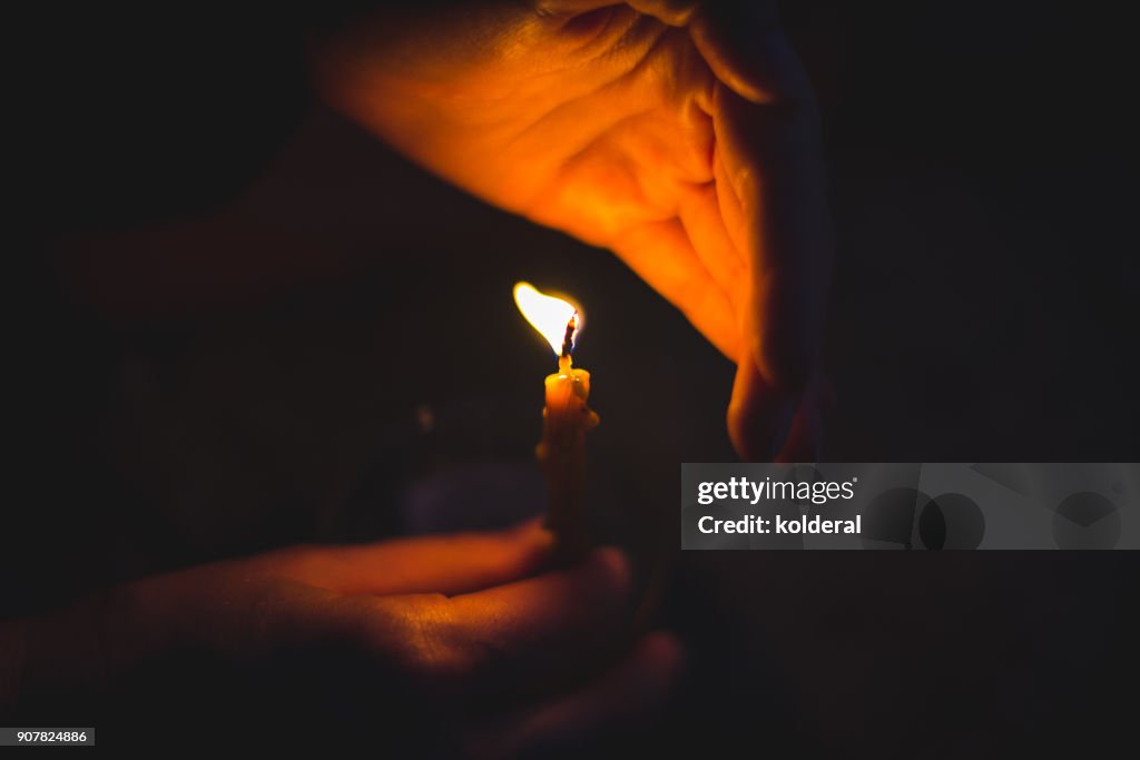 Close-up on candle flame and woman hands