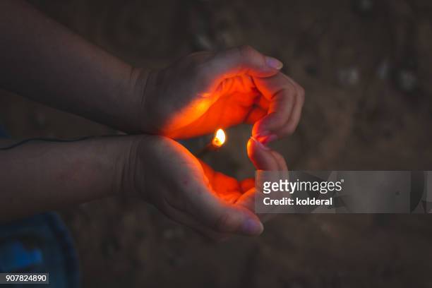 close-up on candle flame and woman hands in shape of heart - hearts on fire stock pictures, royalty-free photos & images