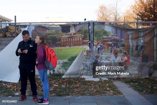 Tourists stand beside a fence of construction near the shuttered Independence Hall after the government shutdown on January 20, 2018 in Philadelphia,...