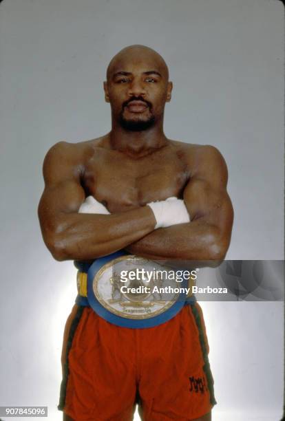 Portrait of American Middleweight boxer Marvin Hagler, his arms crossed, as he poses in shorts and a championship belt, New York, 1980s.